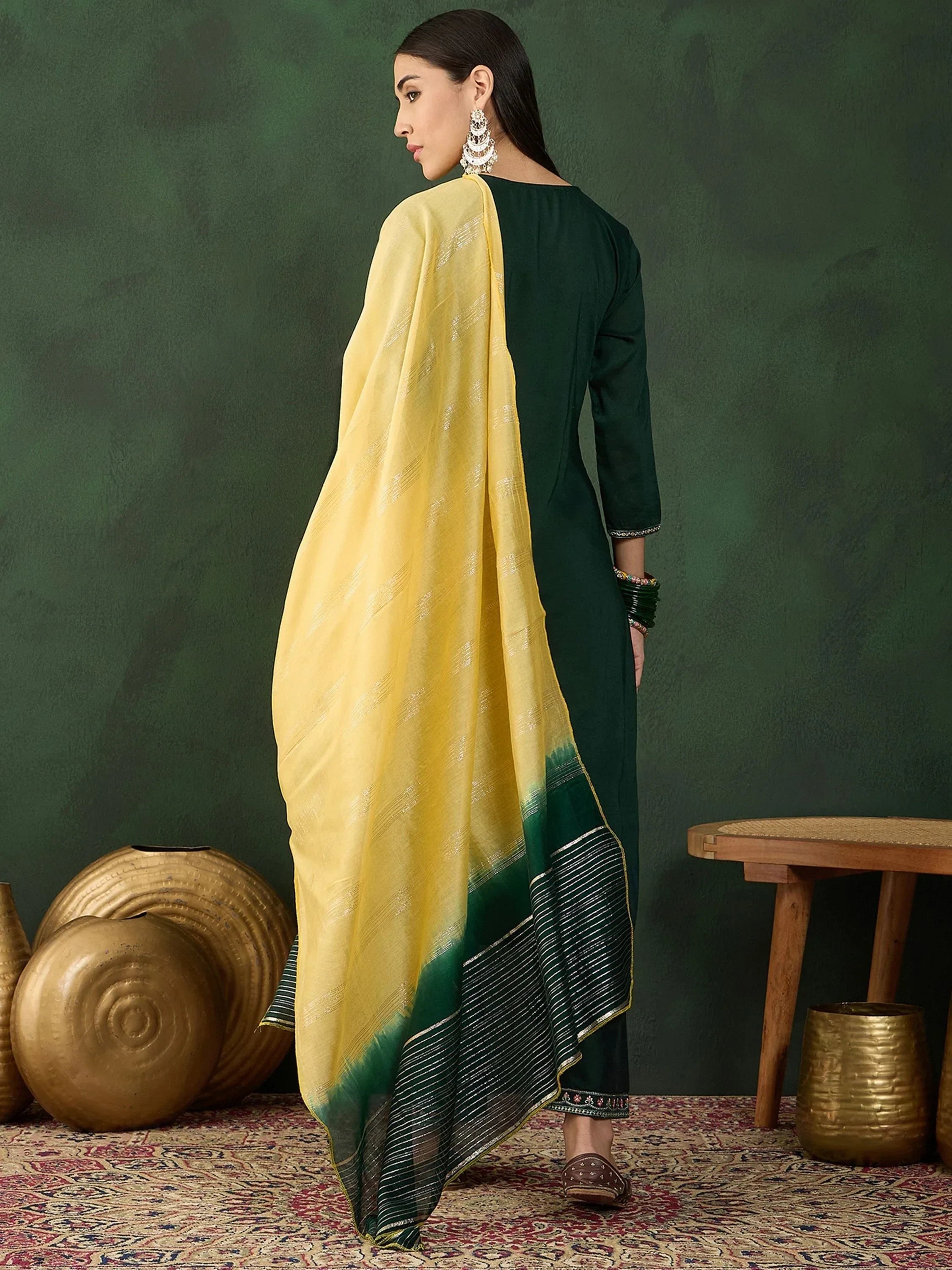 Woman in green salwar kameez with yellow and green dupatta, wearing traditional jewelry