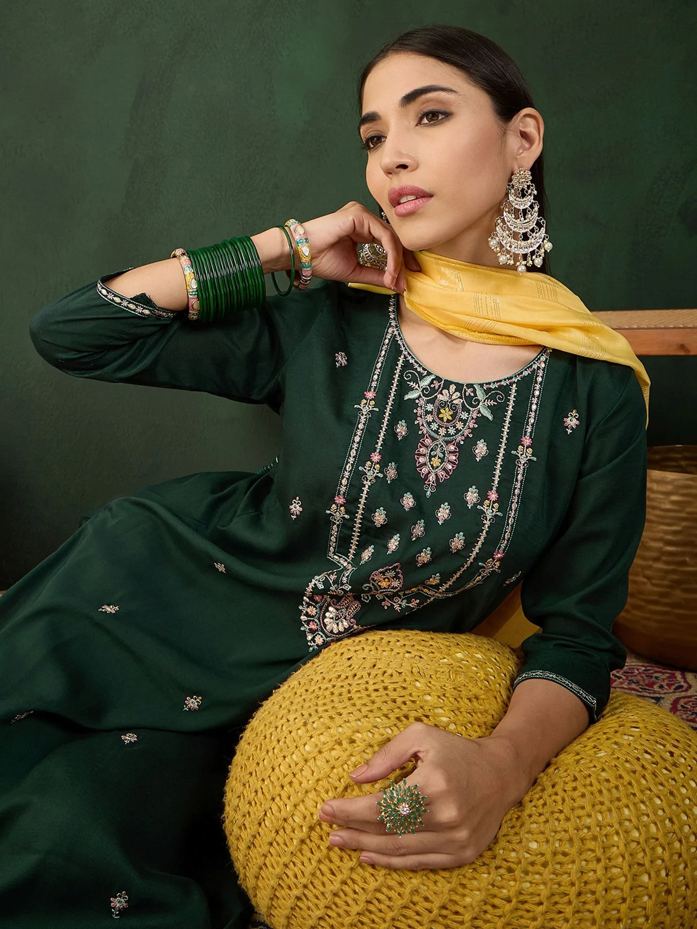 Woman in green embroidered salwar kameez with yellow dupatta and traditional jewelry