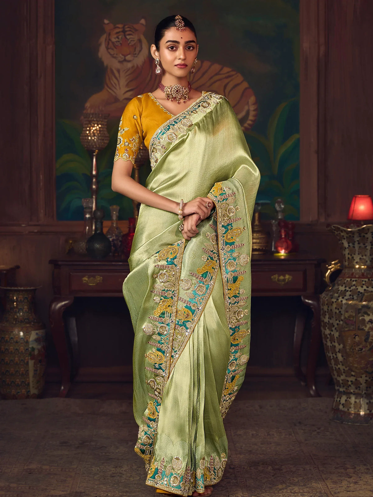 Elegant green saree with gold and teal embroidery, paired with a yellow blouse, perfect for Indian ethnic occasions.
