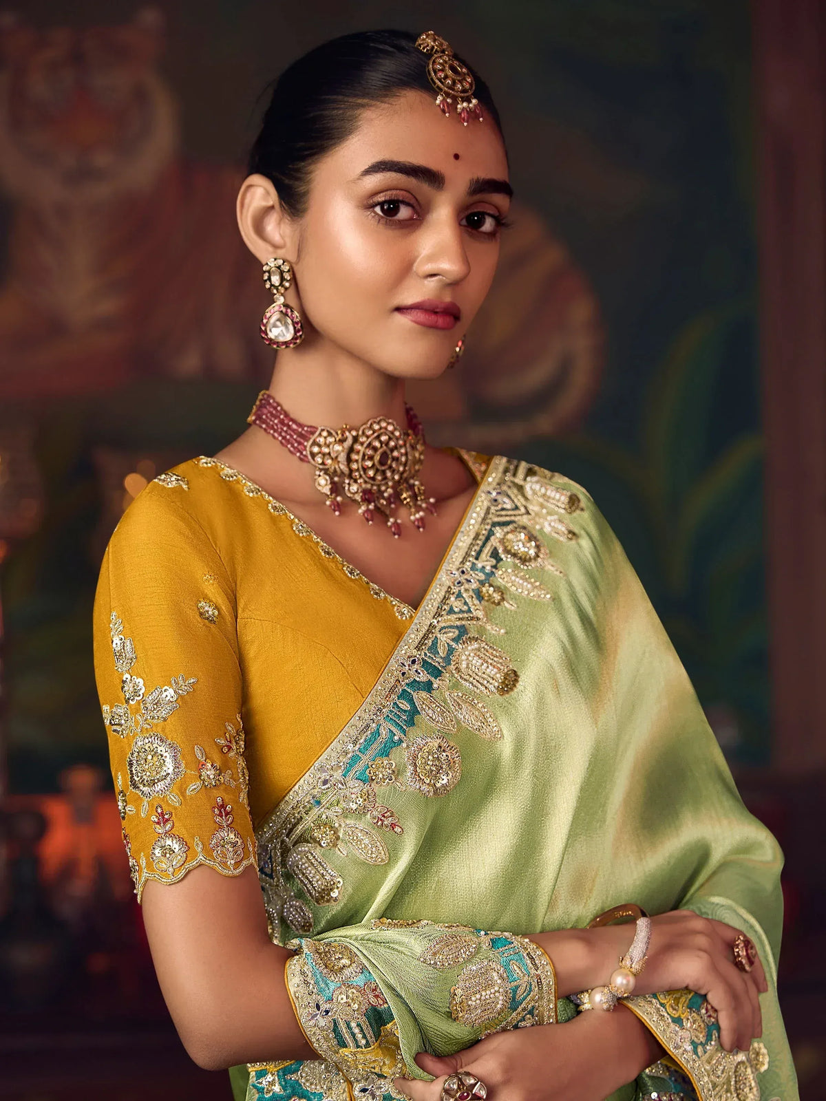Elegant woman in yellow and green embroidered saree with traditional jewelry