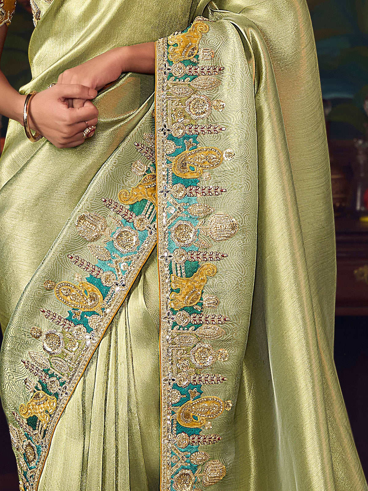 Elegant green saree with intricate gold and turquoise embroidery, perfect for Indian ethnic wear.