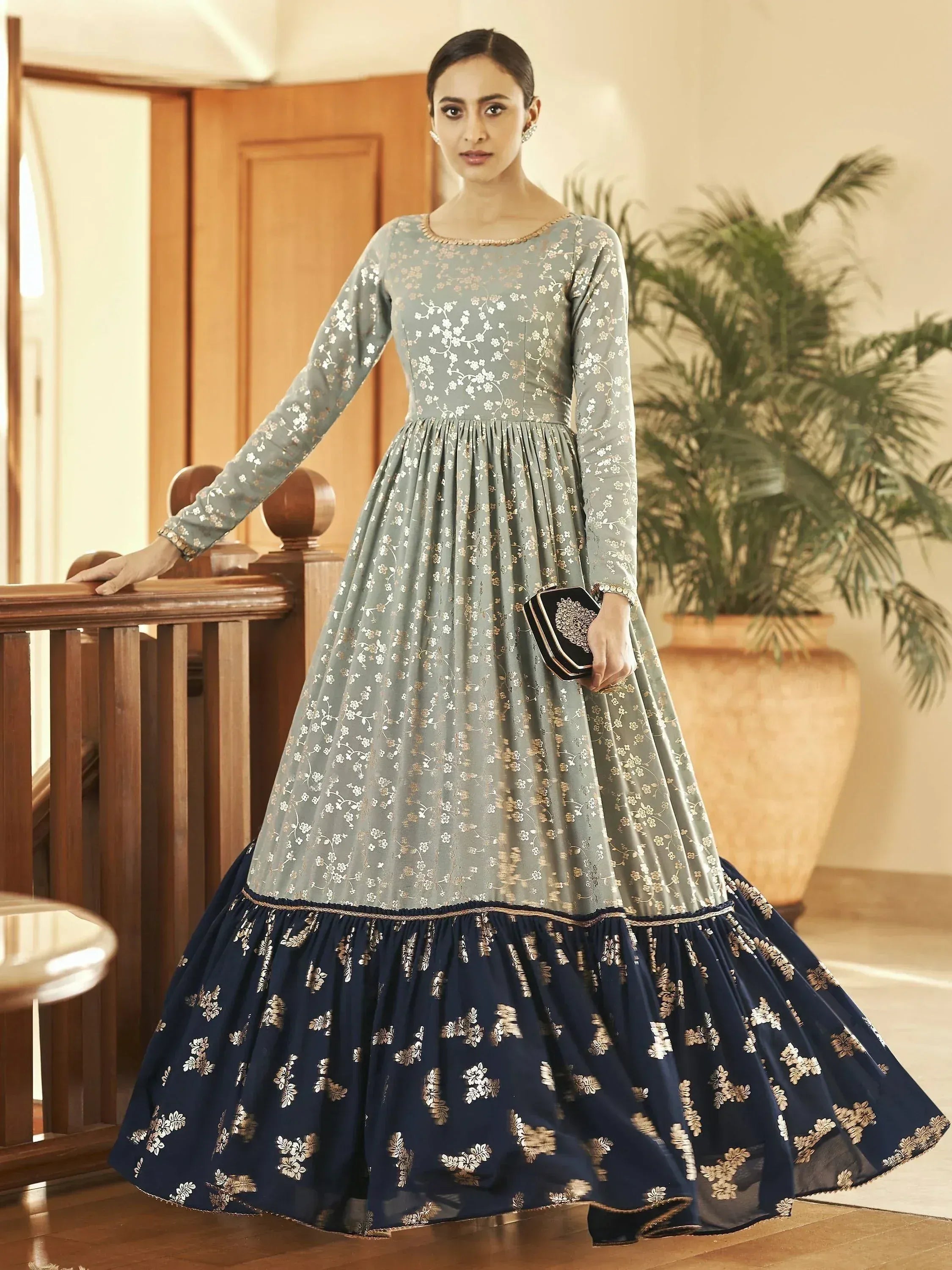 Woman in long sleeve floral embroidered ethnic gown with blue and silver flare skirt indoors