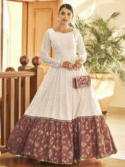 Woman in white and maroon Indian ethnic gown with mirror work, holding embellished clutch