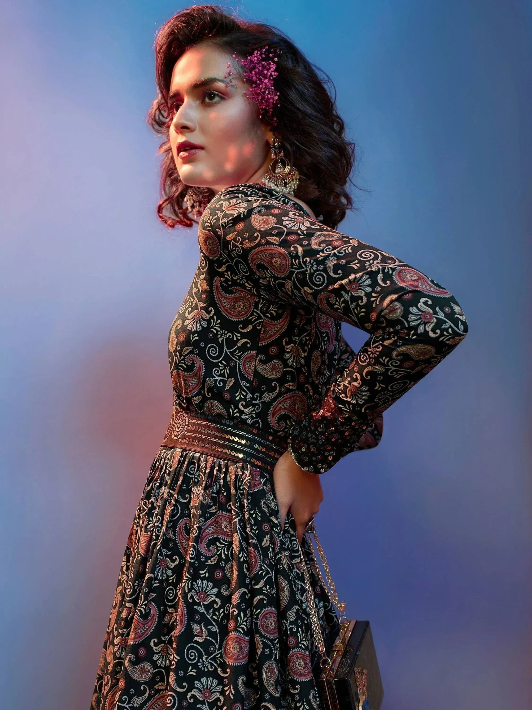 Woman in black paisley print ethnic gown with floral hair accessory and statement earrings