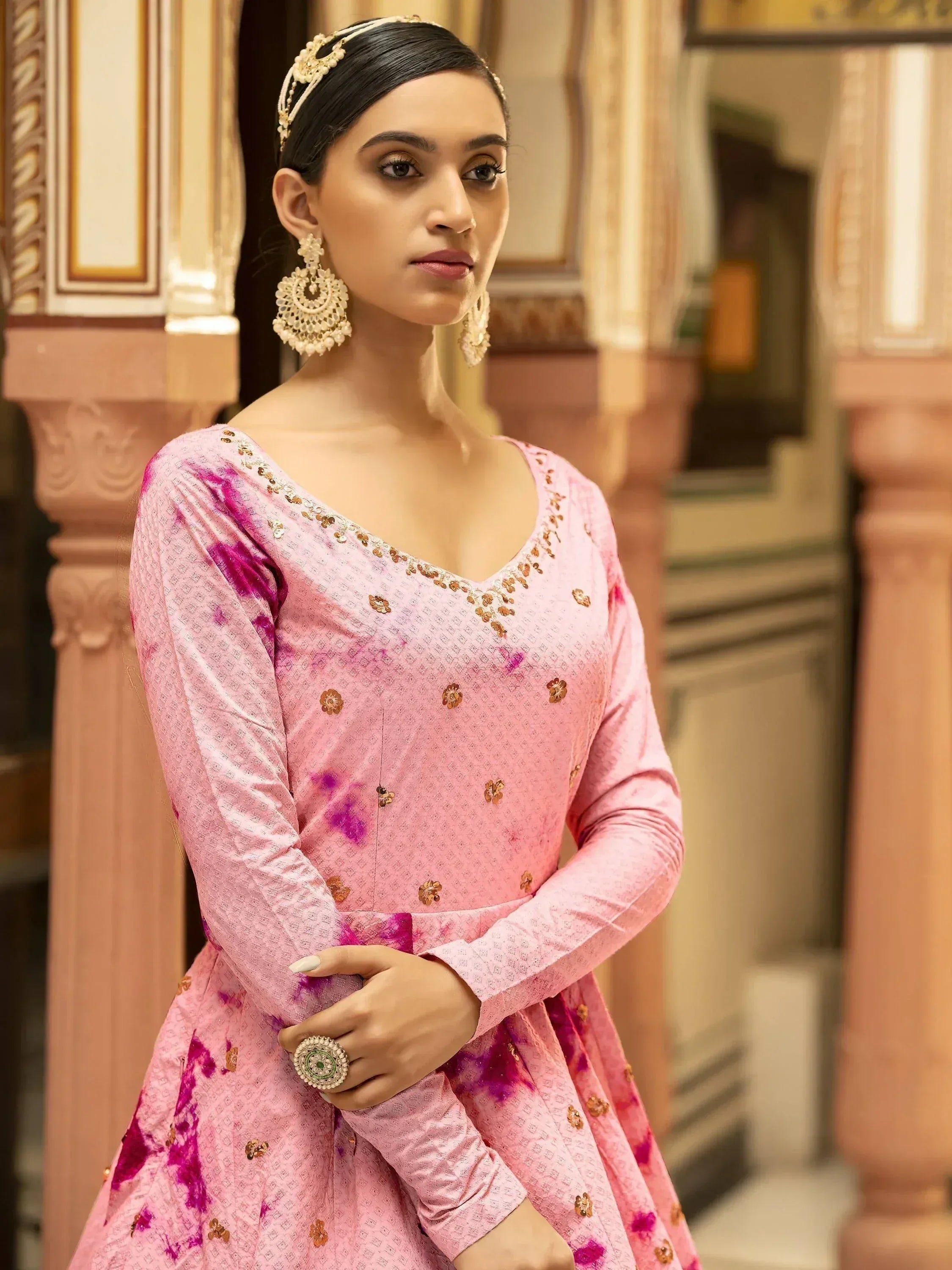 Pink floral embroidered ethnic gown with gold detailing, paired with traditional jewelry for festive occasions.