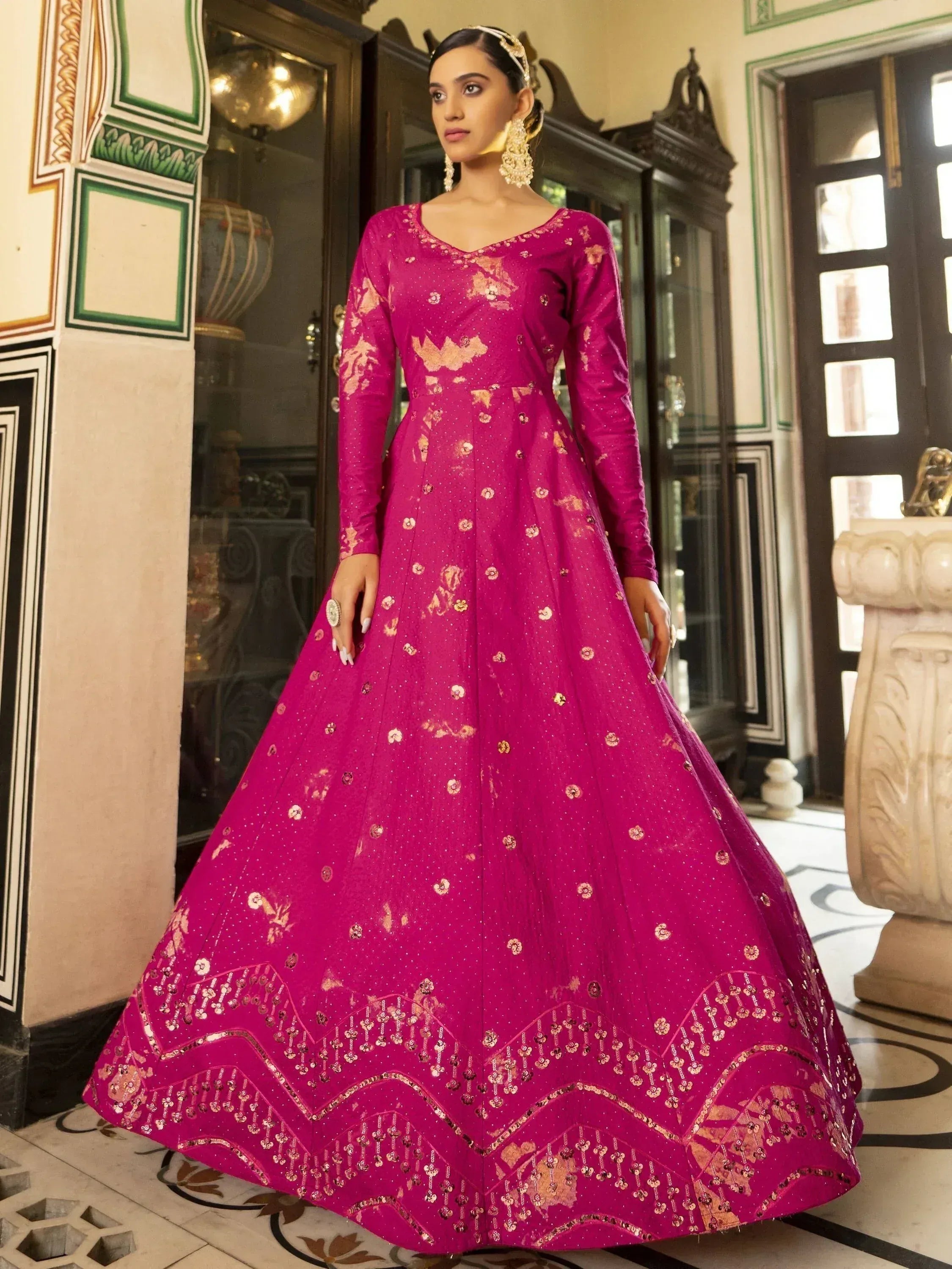 Fuchsia ethnic gown with gold embroidery, perfect for Indian weddings and festive occasions.