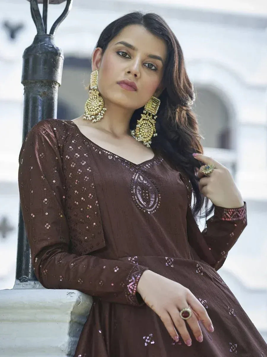 Woman in brown embroidered ethnic gown with gold jhumka earrings, perfect for Indian occasions.