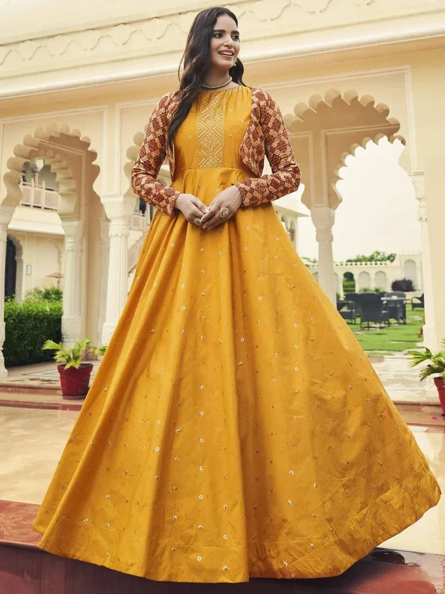 Woman in yellow embroidered ethnic gown with patterned sleeves standing outdoors