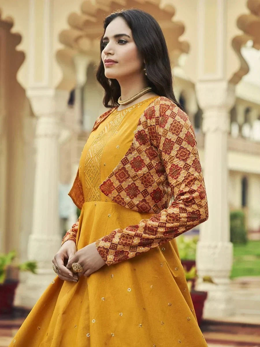 Woman in mustard yellow embroidered ethnic gown with printed long sleeves, outdoor setting