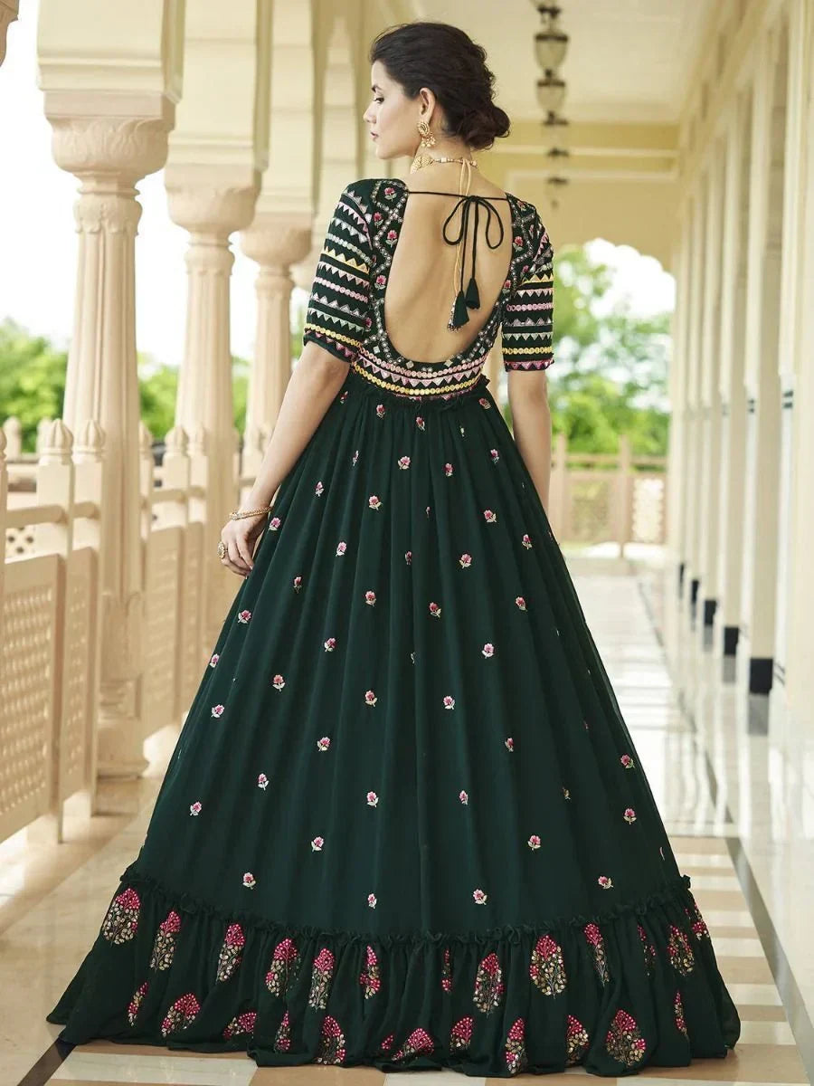 Woman wearing a dark green embroidered Indian gown with open back and floral details.