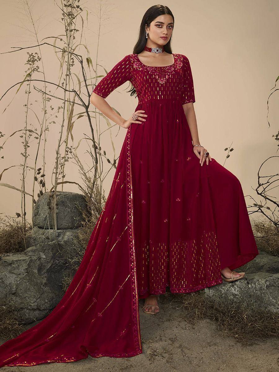 Woman in maroon embroidered ethnic gown with dupatta, standing outdoors