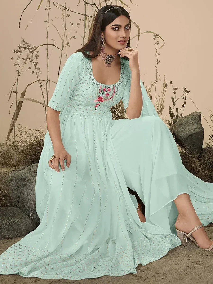 Woman in light blue embroidered ethnic gown with floral design, sitting outdoors