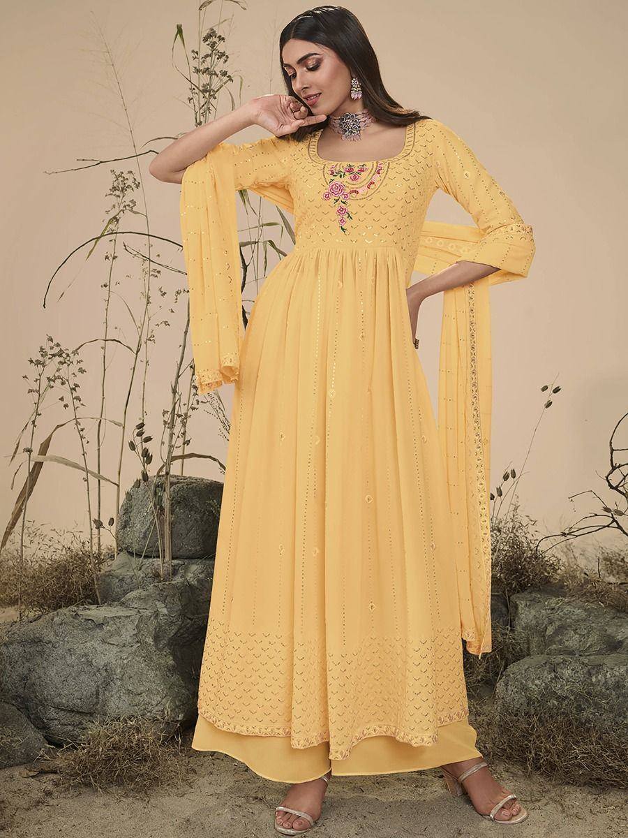 Woman in yellow embroidered Anarkali gown with dupatta, standing outdoors