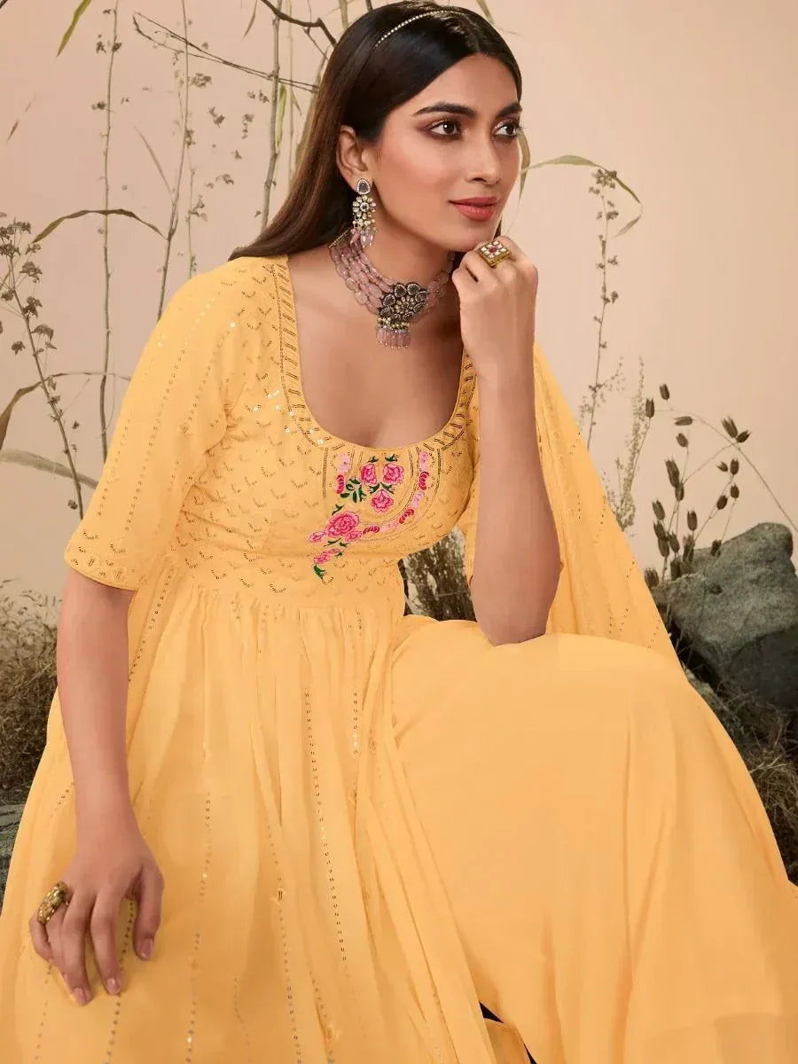 Woman in a yellow embroidered ethnic gown with floral details and statement jewelry