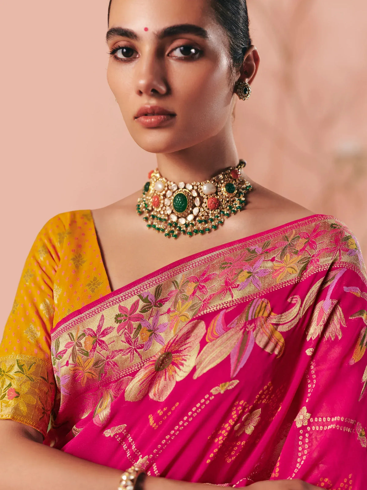 Vibrant pink floral saree with gold embroidery and traditional jewelry