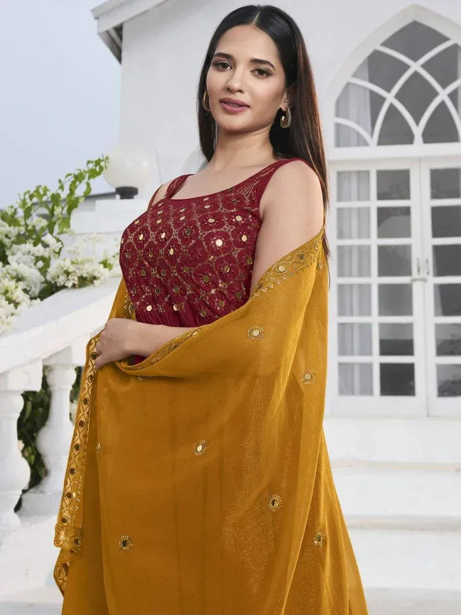 Woman in maroon embroidered lehenga choli with golden dupatta, outdoor ethnic fashion