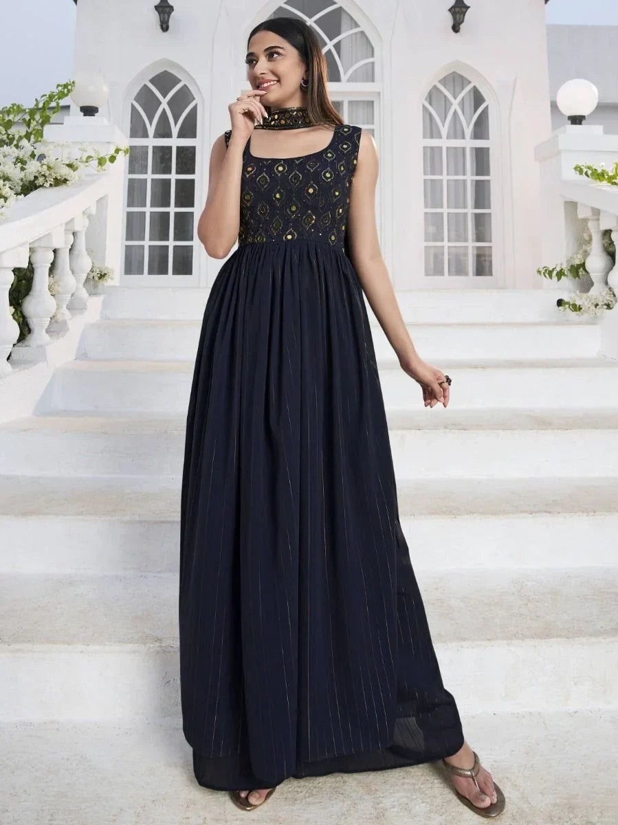 Woman wearing a sleeveless navy blue ethnic gown with embroidered bodice on white steps outdoors