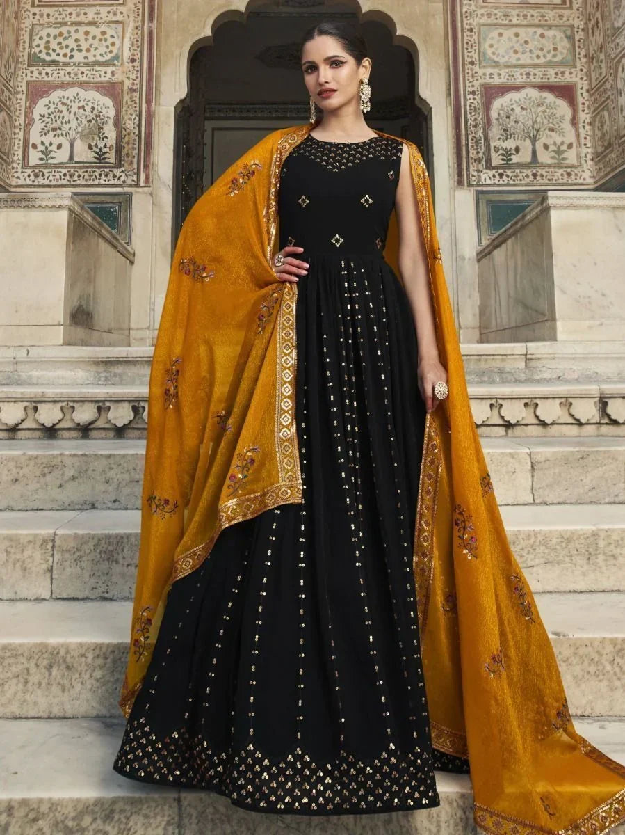 Woman in black ethnic gown with gold embellishments and mustard embroidered dupatta