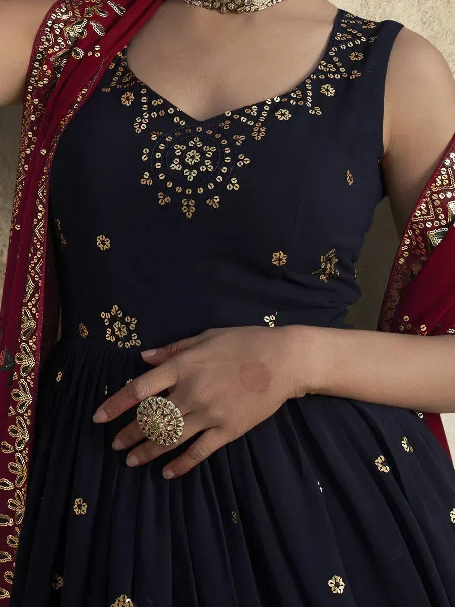 Navy blue ethnic gown with gold floral embroidery, paired with maroon dupatta and statement jewelry