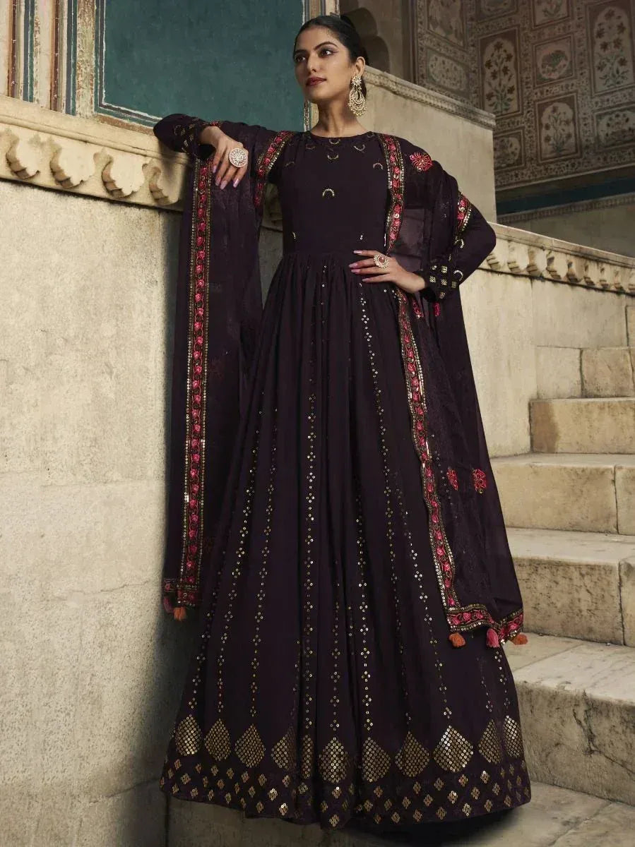 Elegant dark purple ethnic gown with gold and pink embroidery, styled with traditional jewelry.
