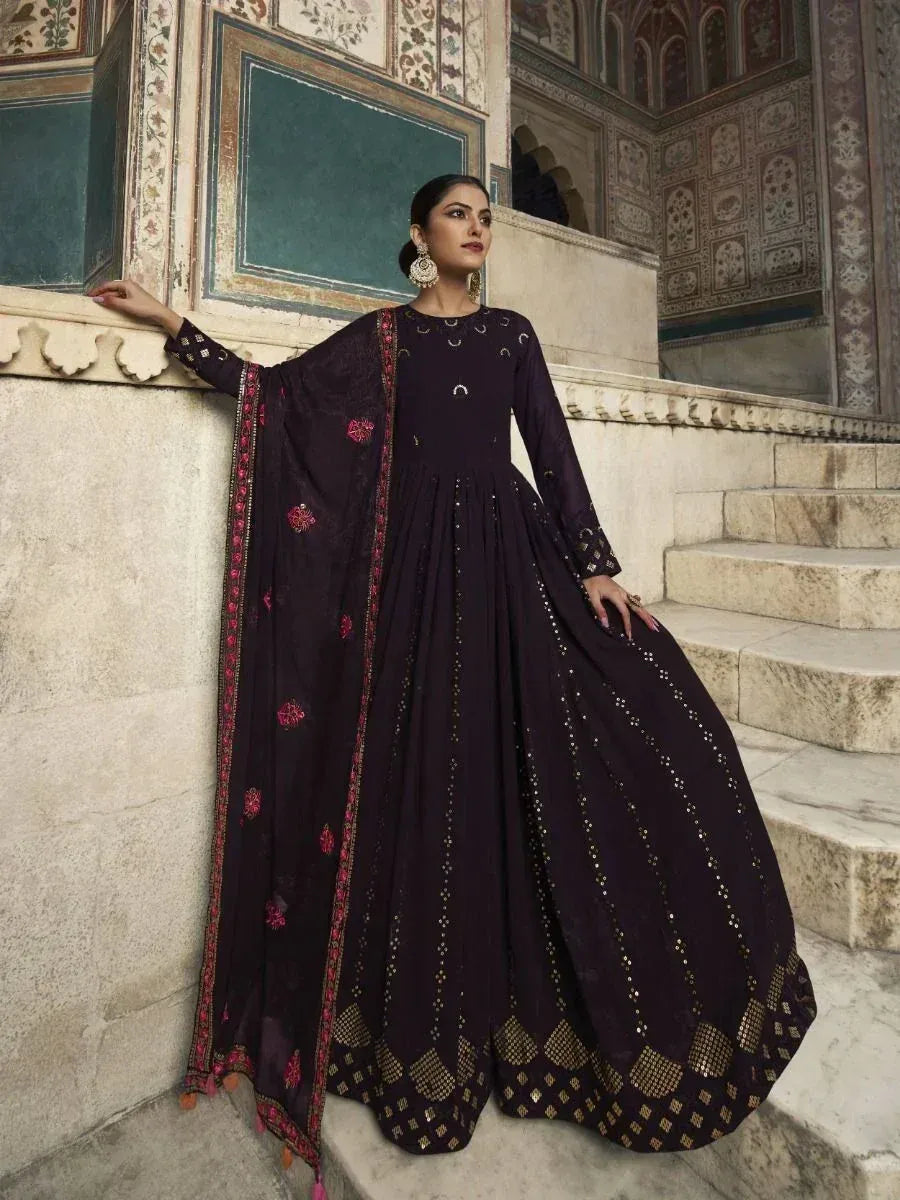 Elegant dark purple anarkali gown with gold embroidery and pink floral dupatta, perfect for Indian ethnic occasions.