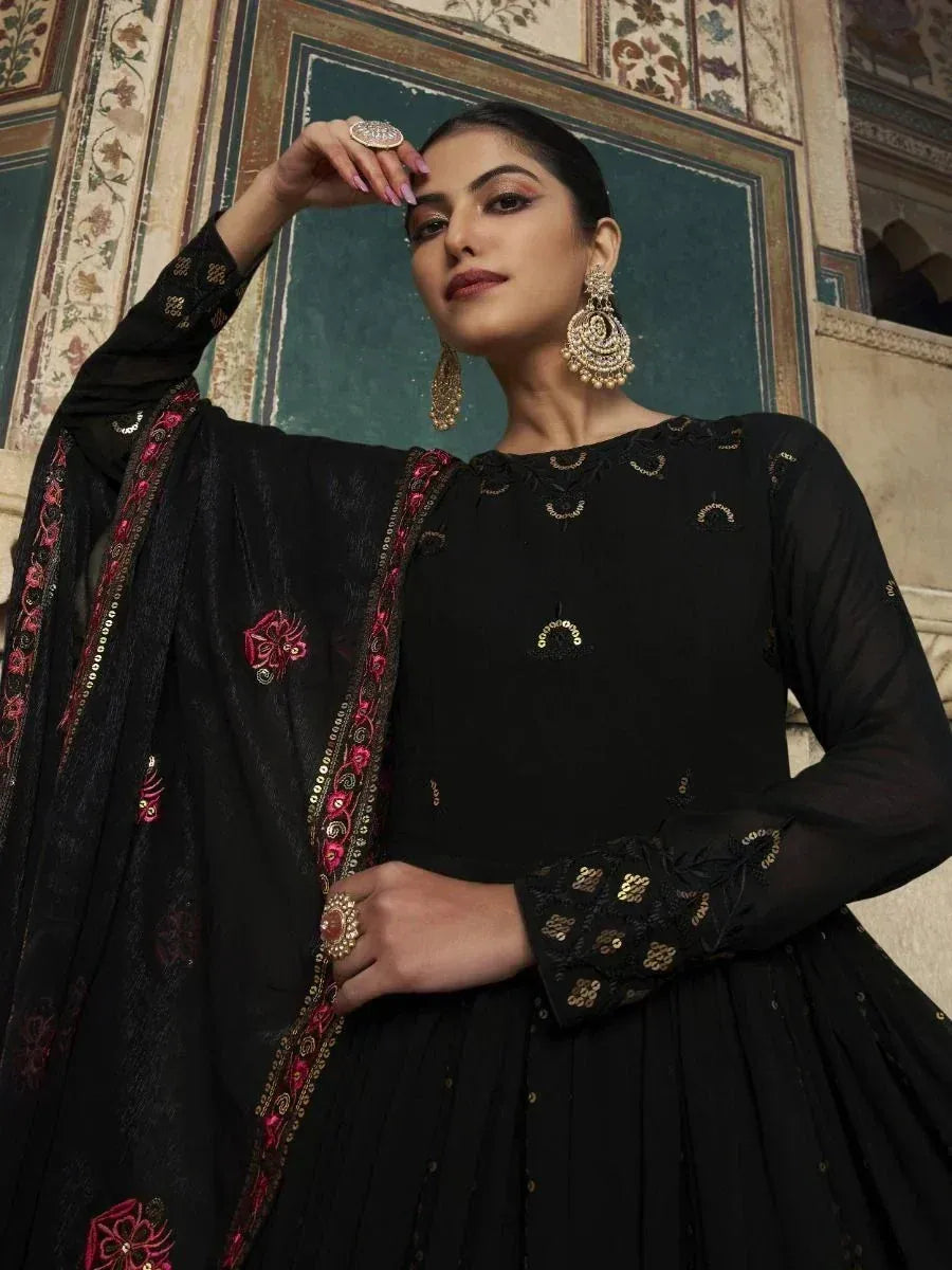 Black embroidered ethnic gown with pink and gold detailing, paired with statement jewelry for festive occasions