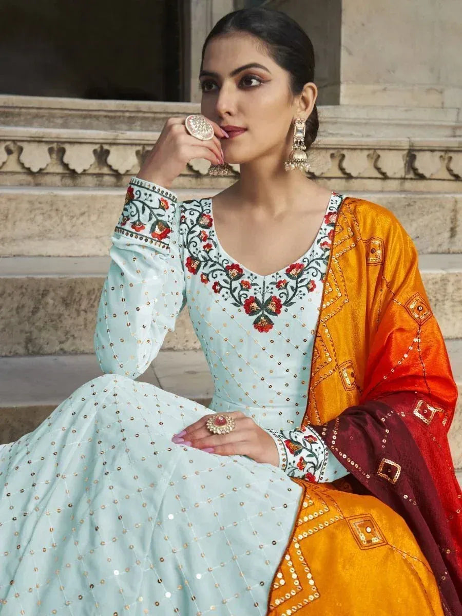Woman in light blue embroidered salwar kameez with orange dupatta, floral neckline, and mirror work