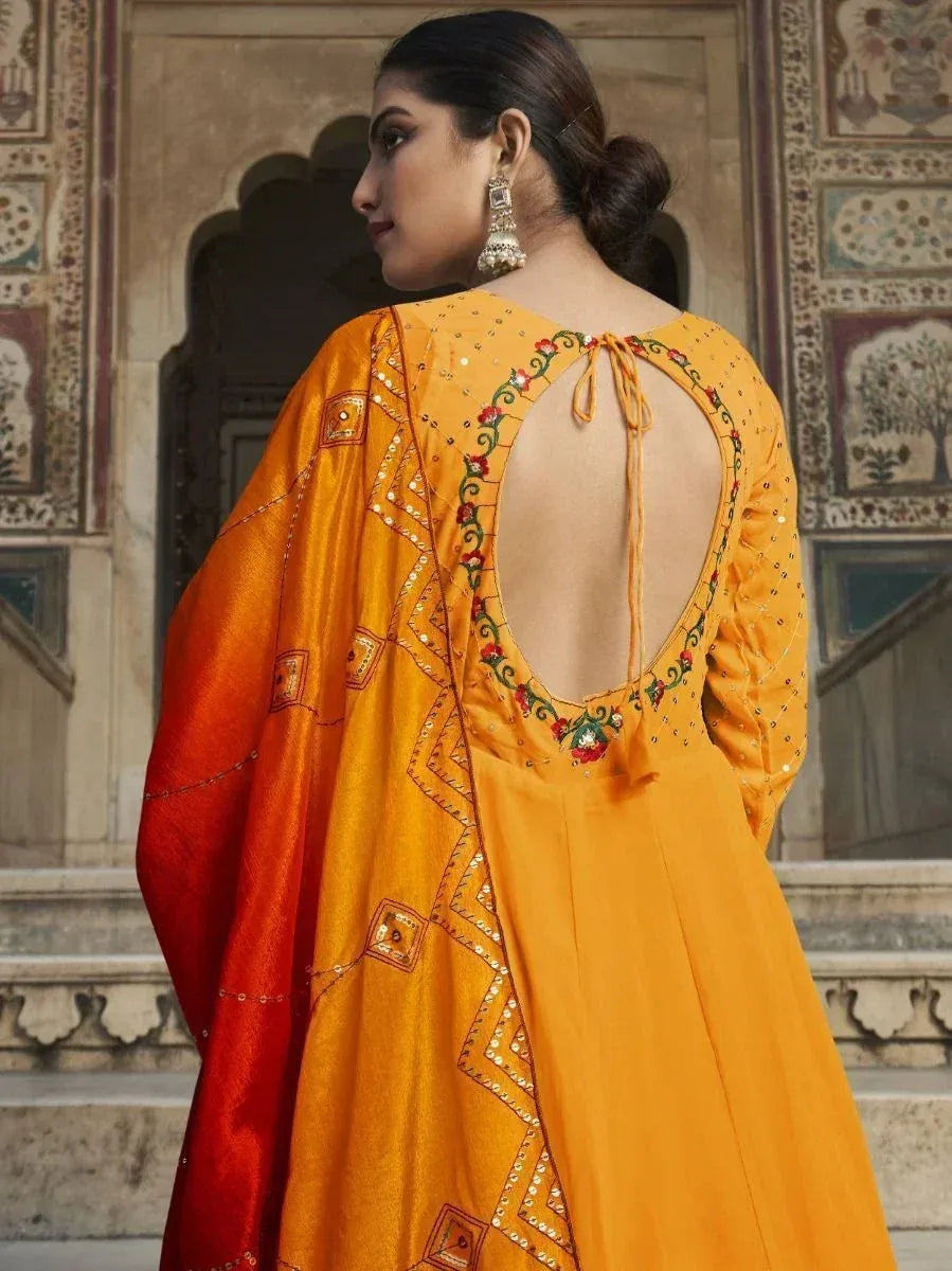 Orange ethnic gown with back cutout, floral embroidery, and red dupatta, perfect for Indian occasions