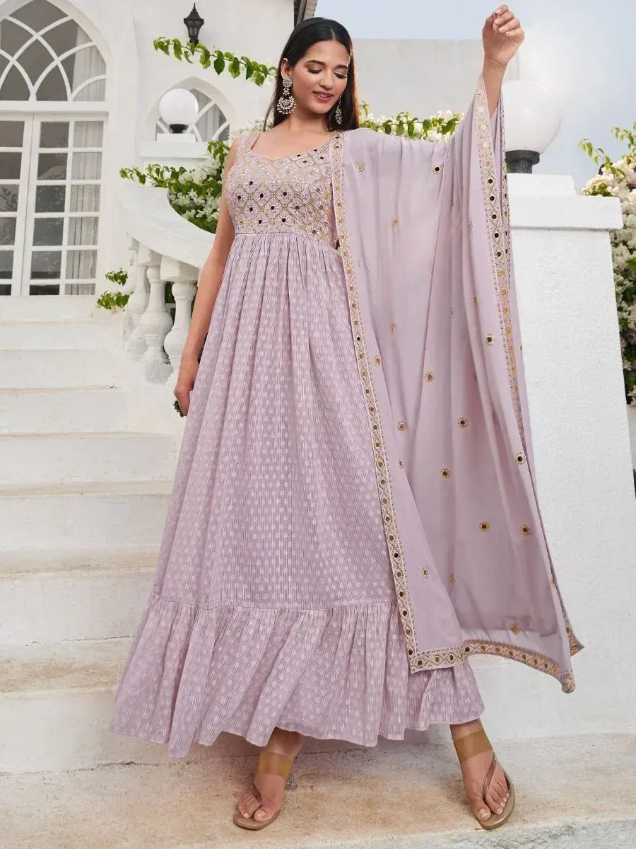 Woman in lavender embroidered ethnic gown with dupatta, standing on white stairs outdoors