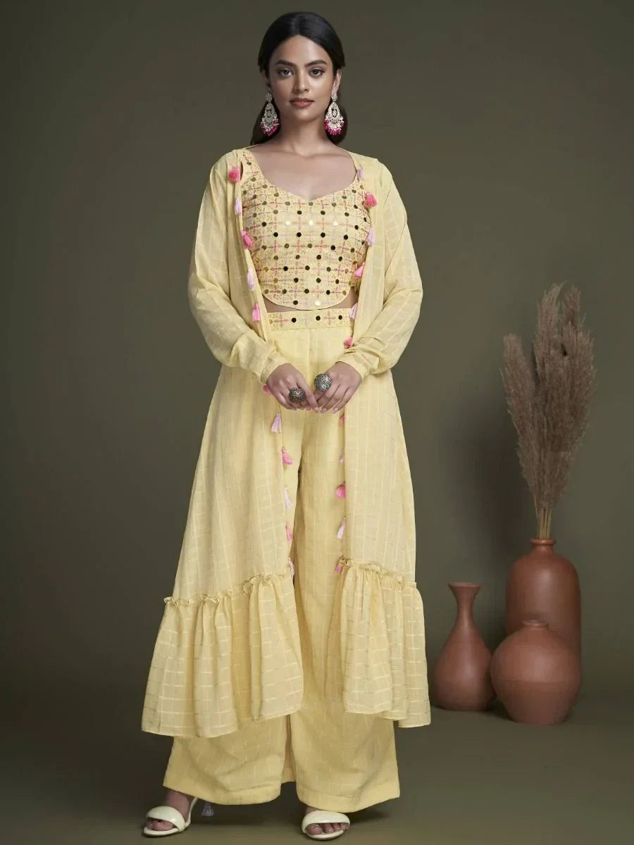 Woman in yellow ethnic palazzo suit with embroidered crop top and tassel dupatta
