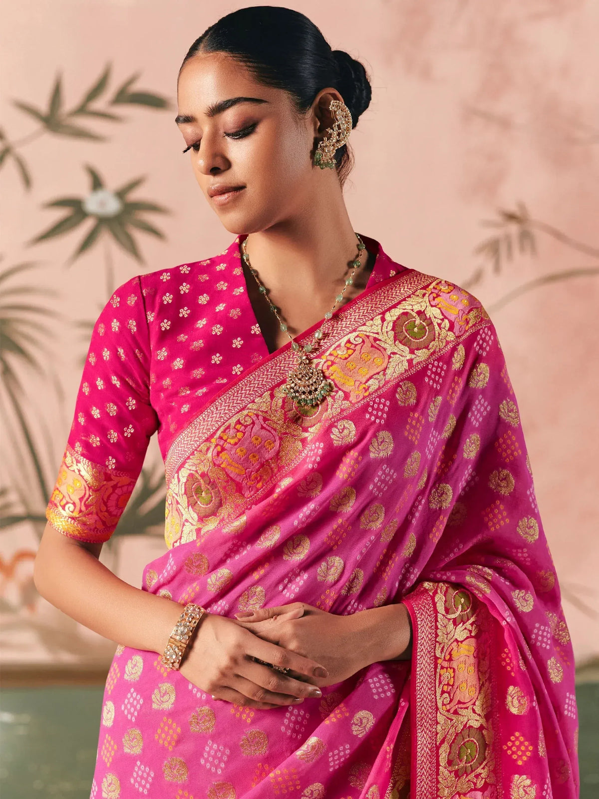 Pink designer saree with gold embroidery and floral patterns, paired with traditional jewelry