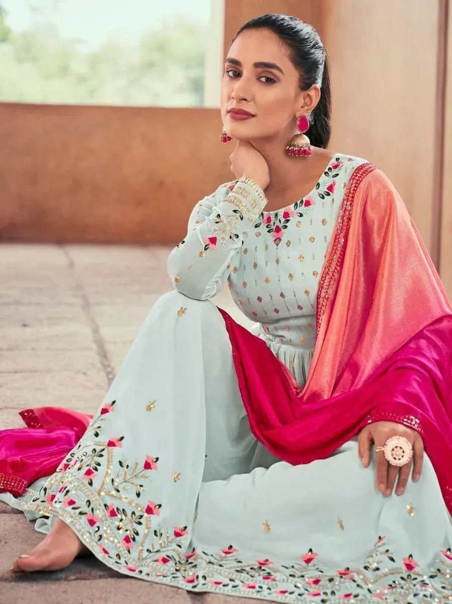 Woman in light blue embroidered salwar kameez with pink dupatta and ethnic jewelry