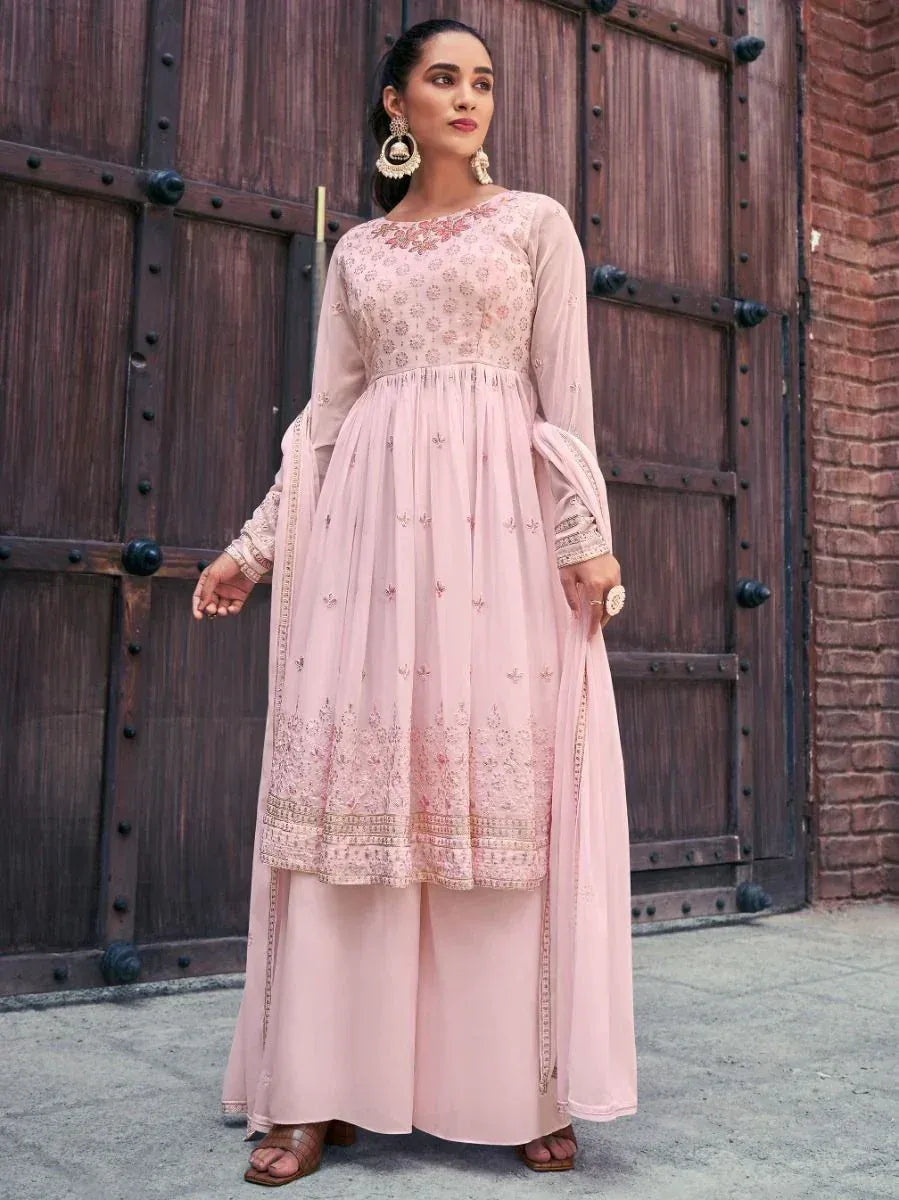 Woman in a pastel pink embroidered Indian ethnic suit with palazzo pants and dupatta