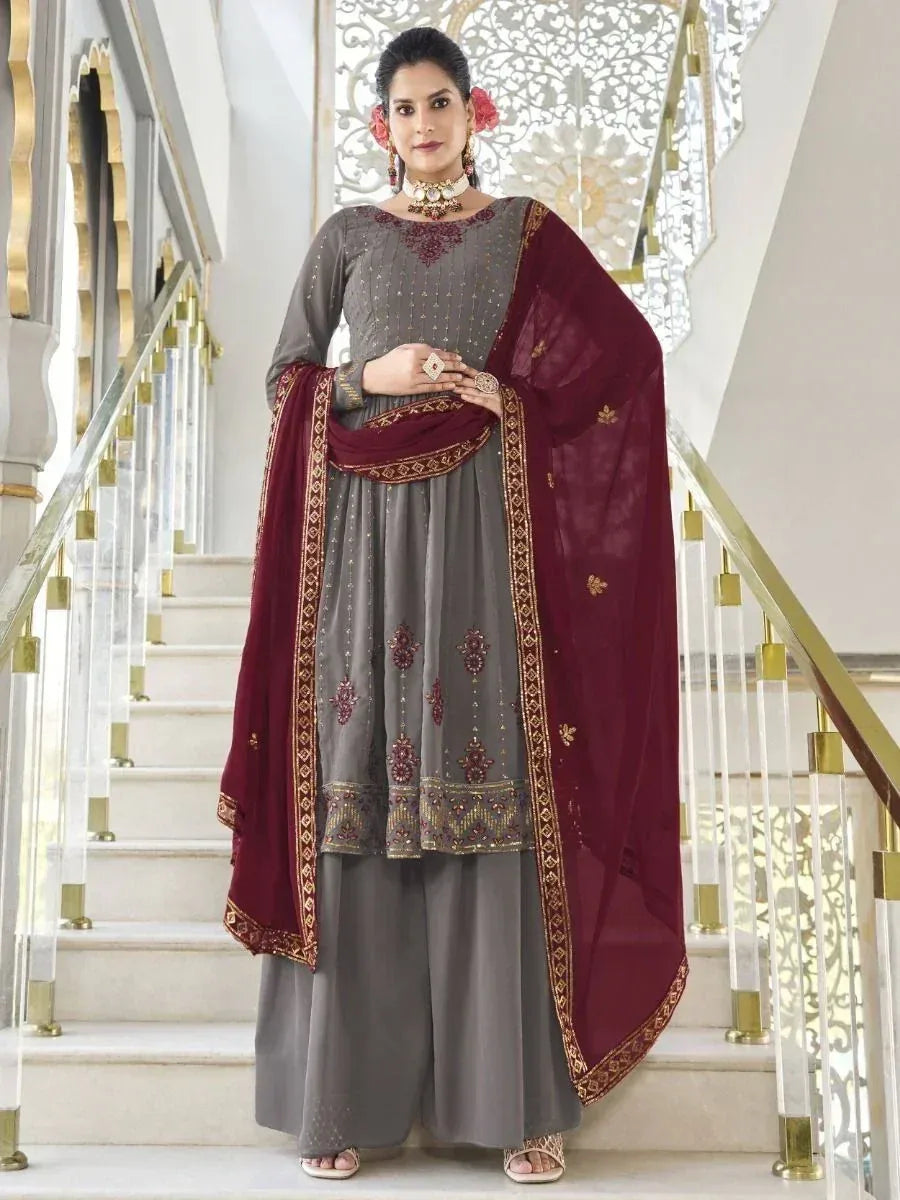 Woman in grey and maroon embroidered salwar kameez with dupatta on staircase