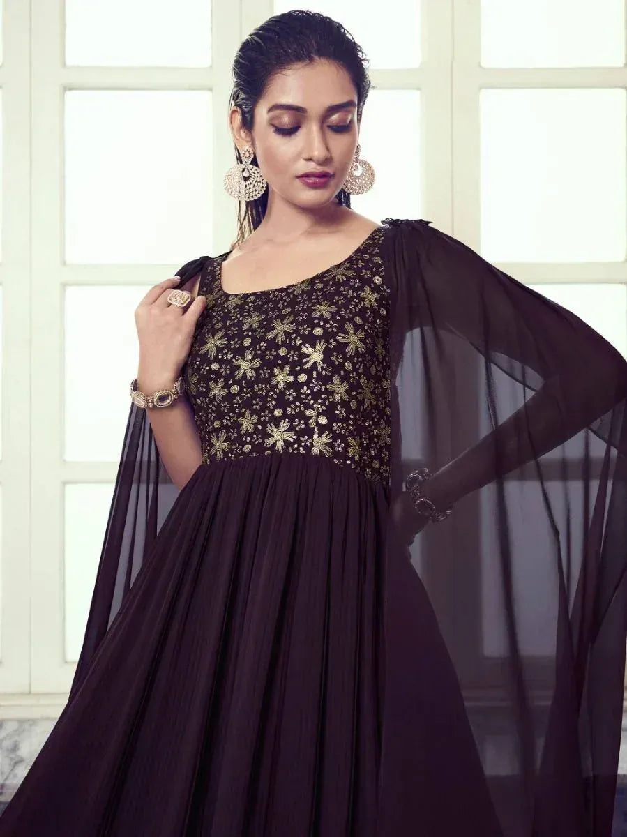 Black ethnic gown with gold floral embroidery and sheer cape sleeves, perfect for Indian occasions.