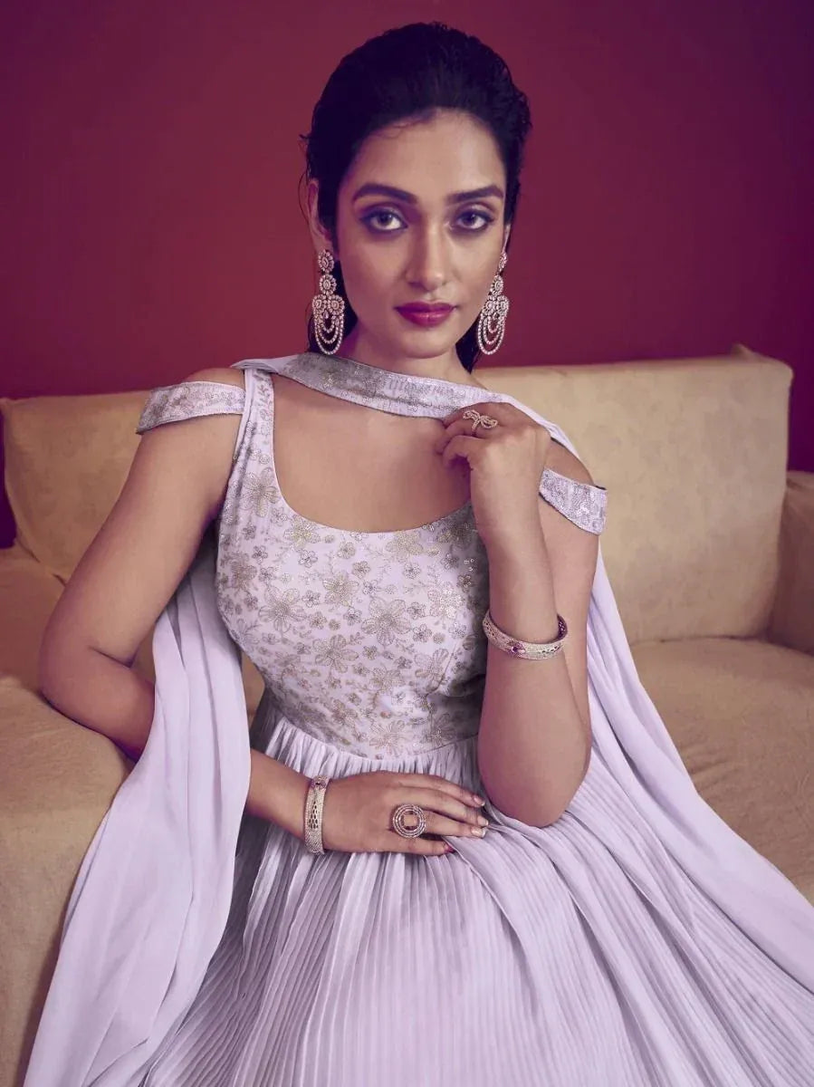 Elegant lavender ethnic gown with floral embroidery, pleated skirt, and statement jewelry for festive occasions