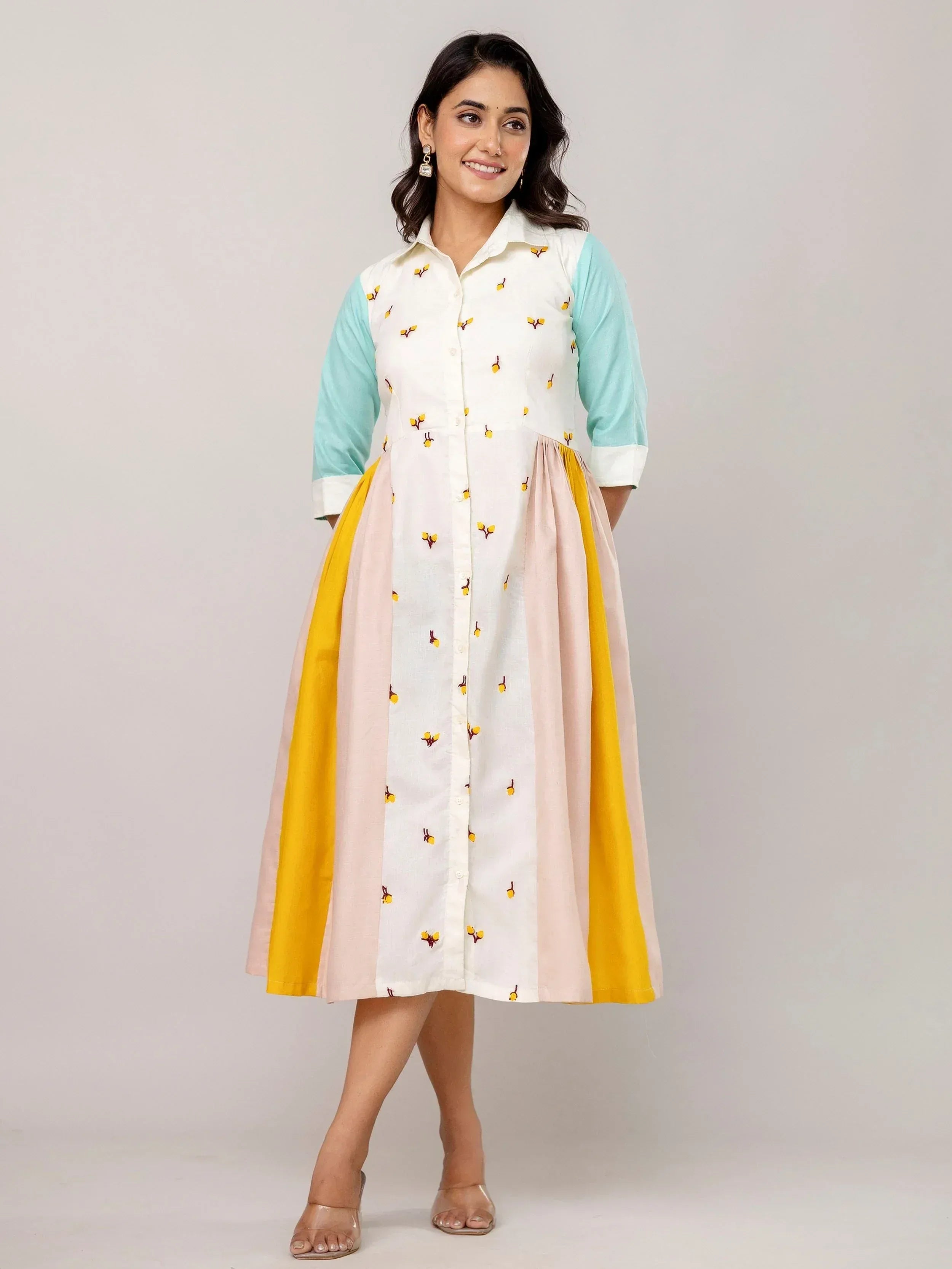 Woman in embroidered white, mint, and yellow ethnic gown with floral details, perfect for Indian occasions.