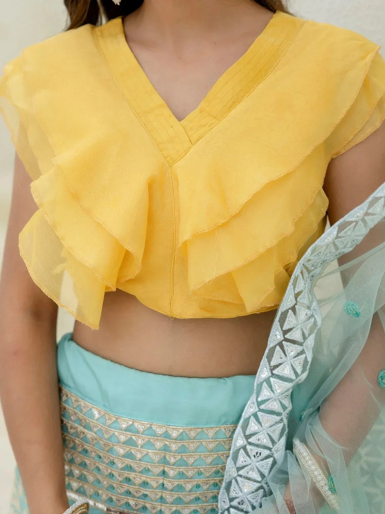 Yellow ruffle crop top with V-neck paired with turquoise embroidered lehenga and dupatta