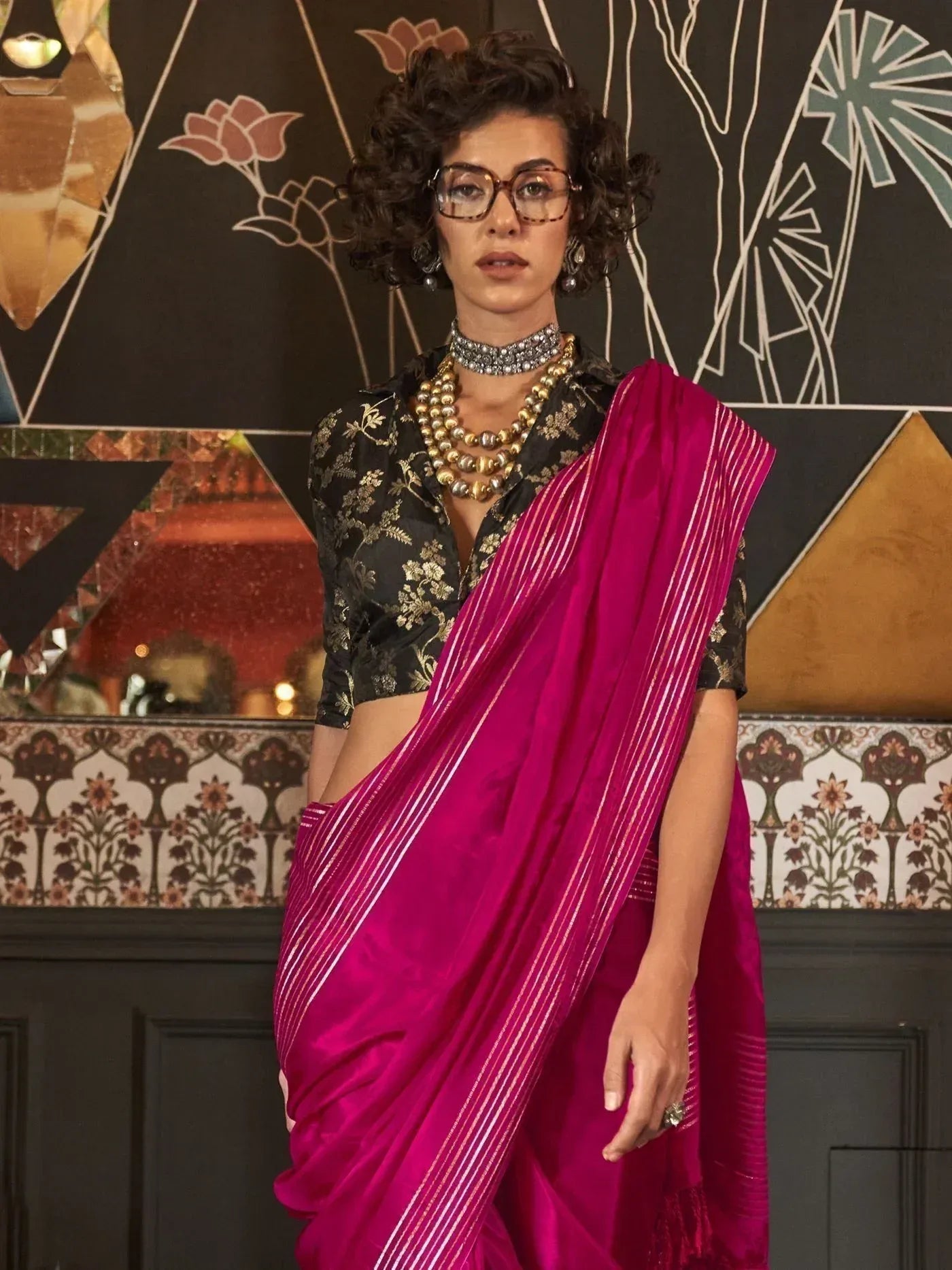 Vibrant pink striped saree with gold floral blouse, styled with statement jewelry for ethnic wear.