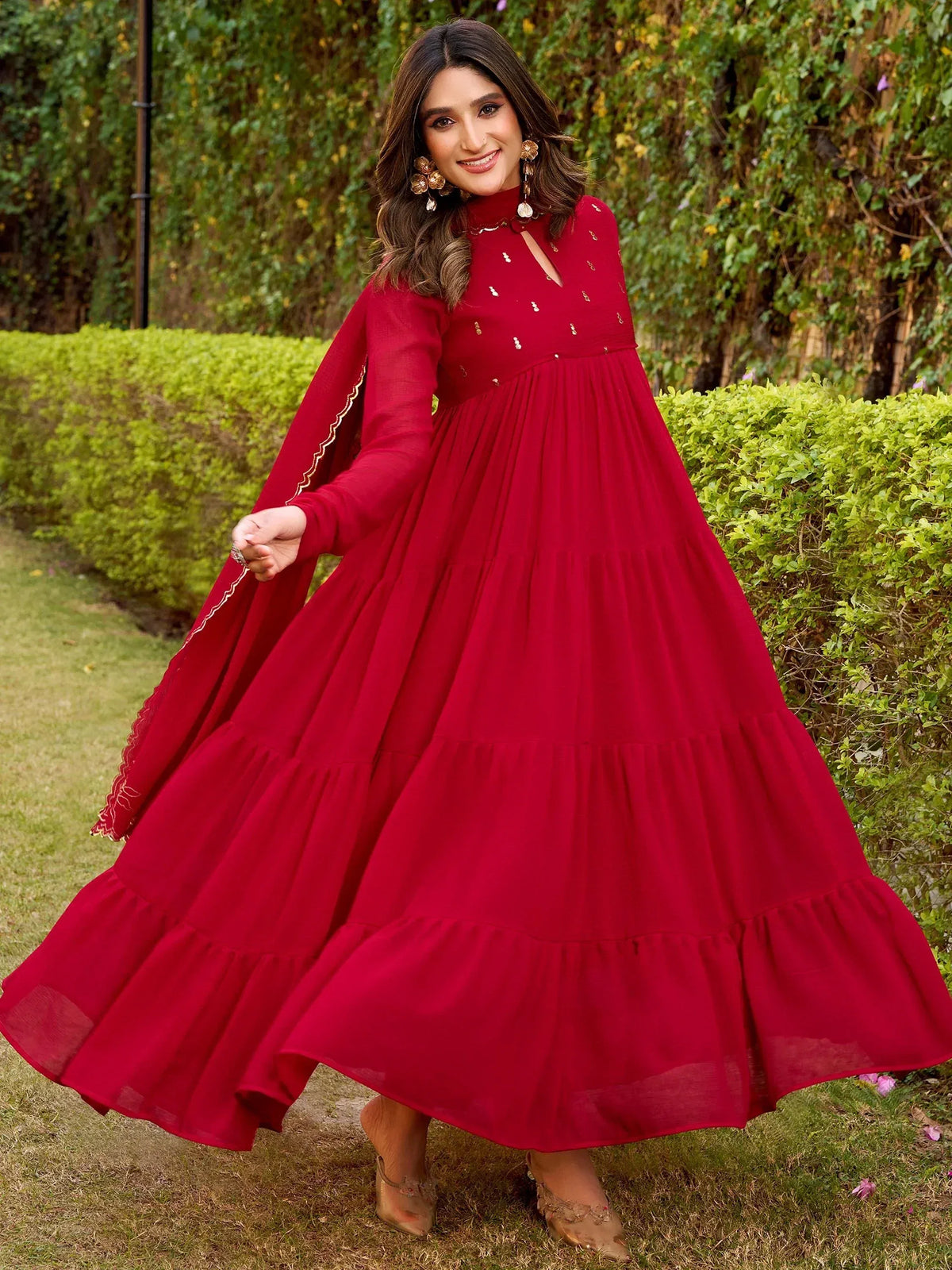 Red ethnic gown with gold embroidery, tiered skirt, and flared sleeves for festive occasions