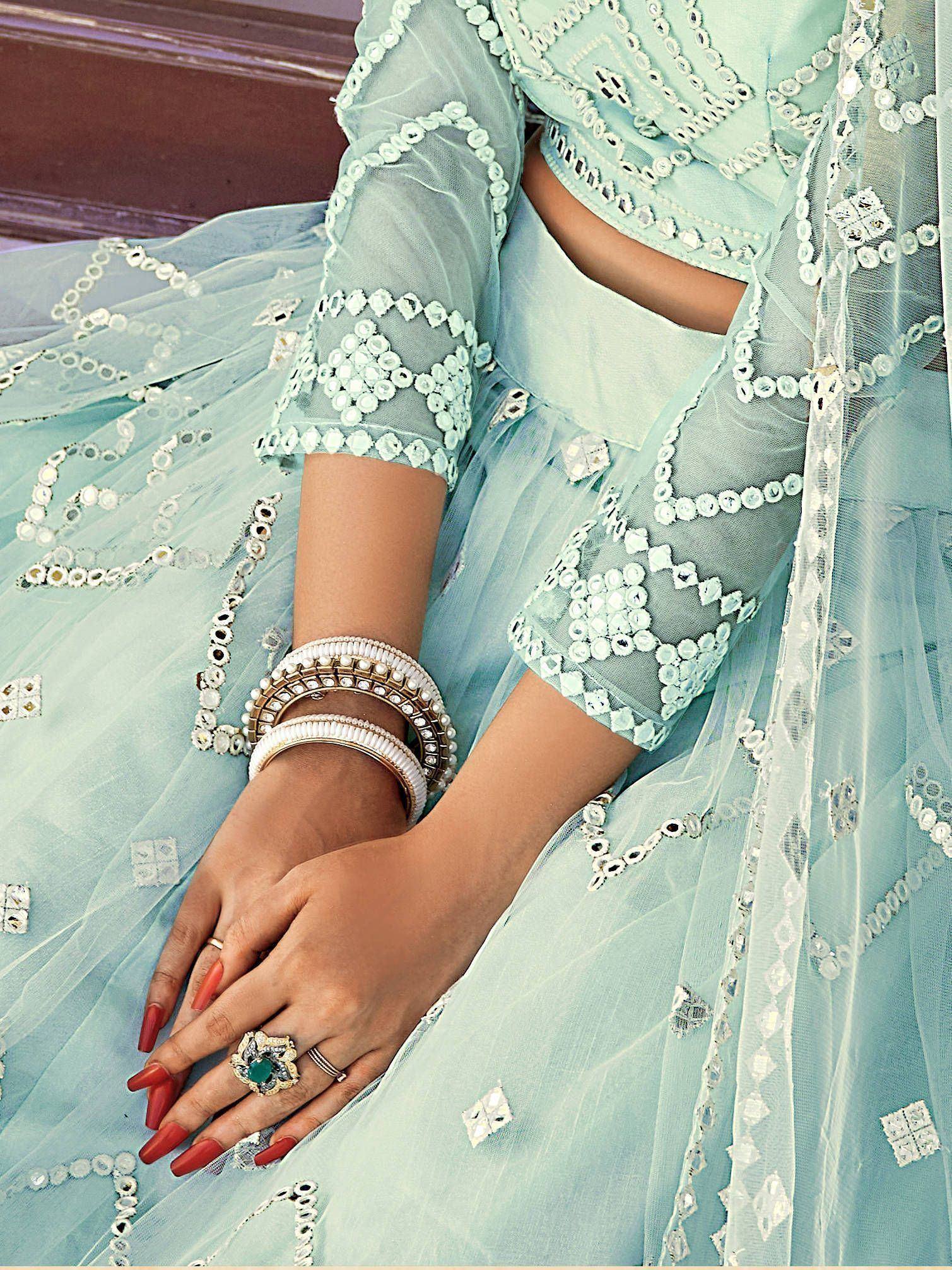 Mint green designer lehenga choli with mirror work, paired with traditional bangles and ring for Indian ethnic wear.