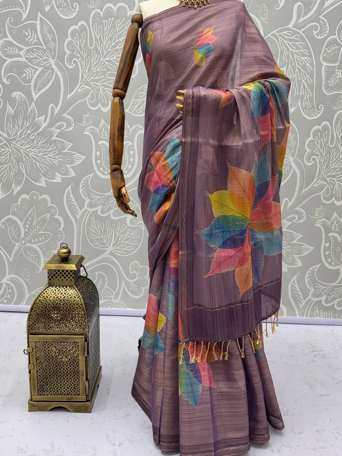 Purple designer saree with colorful leaf prints on a mannequin