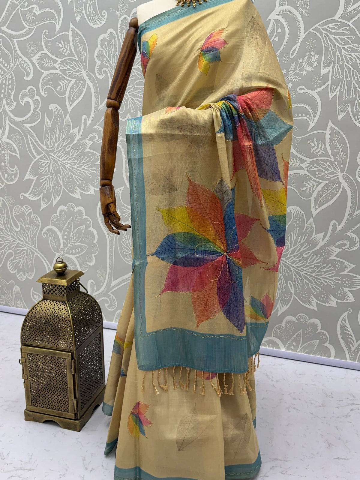 Beige ethnic saree with colorful floral motifs and blue border on a mannequin