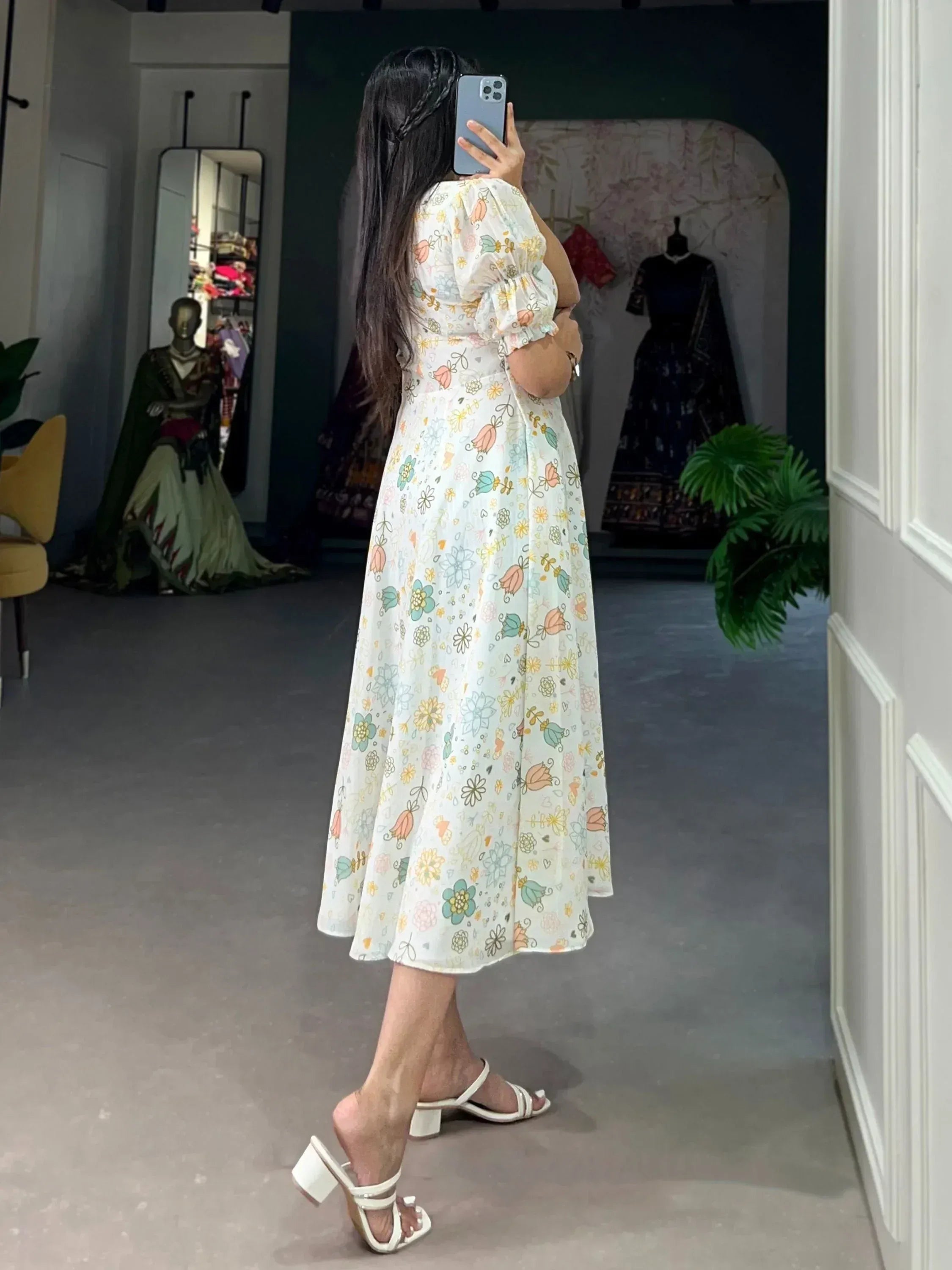 Woman in floral print ethnic gown with puff sleeves, mirror selfie in boutique