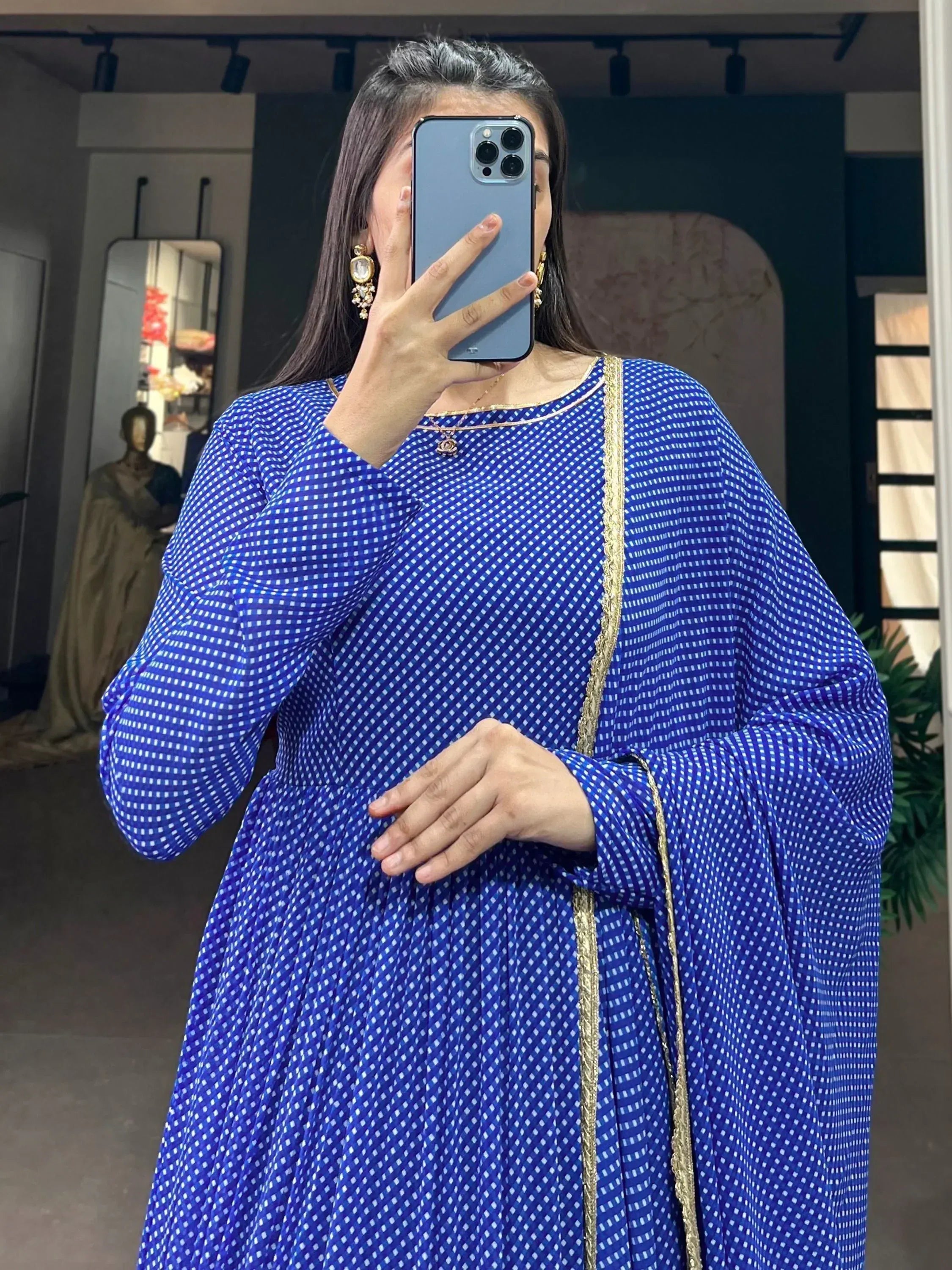 Blue ethnic gown with white checks and gold trim, styled with statement earrings for festive occasions.
