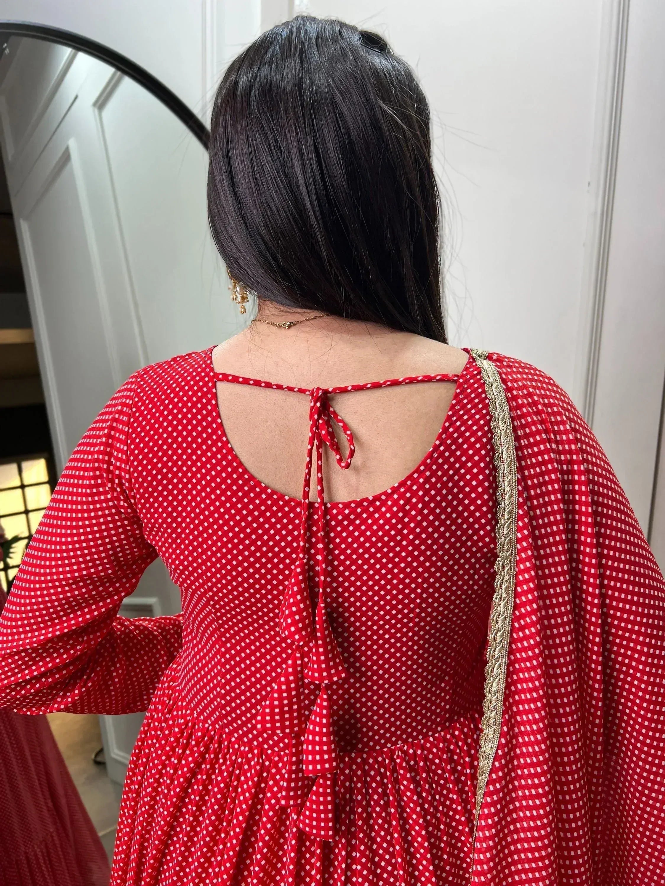 Red ethnic gown with white checks, back tie detail, and gold trim, perfect for Indian festive wear.