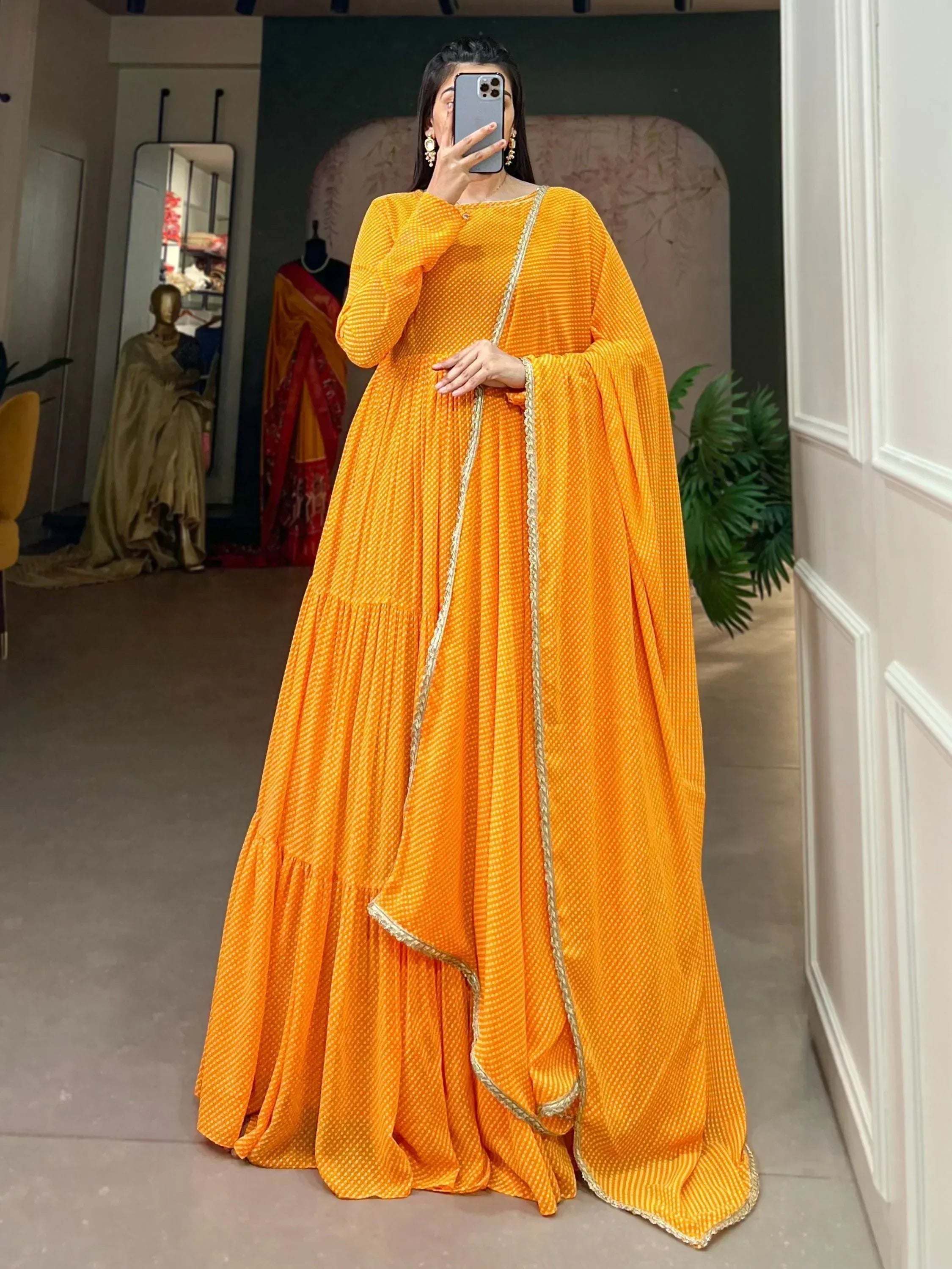 Vibrant orange ethnic gown with gold trim, perfect for Indian occasions and festive wear.