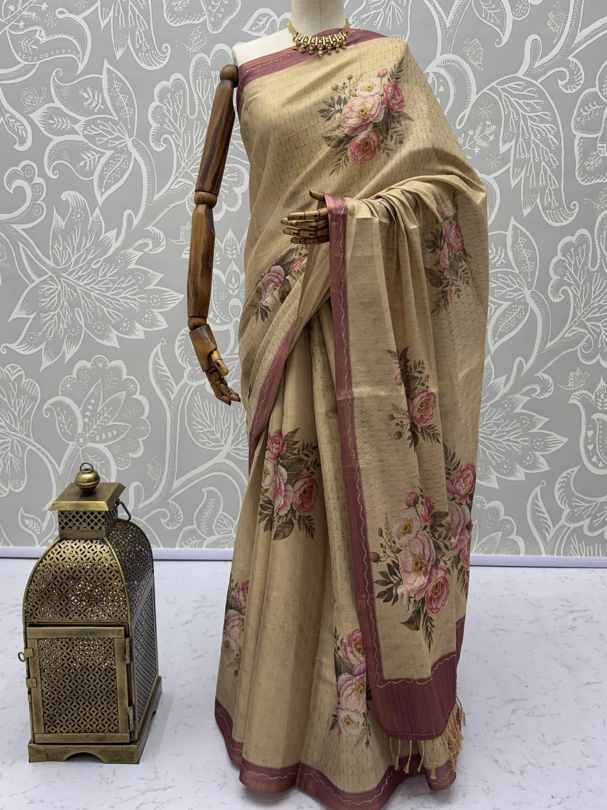 Beige floral print saree with a maroon border displayed on a mannequin.
