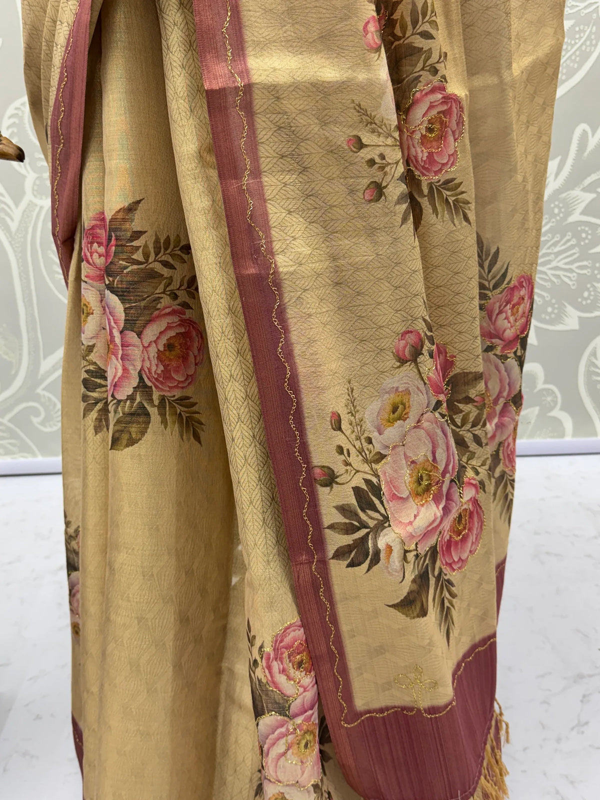 Beige Indian ethnic saree with pink floral prints and a maroon border.