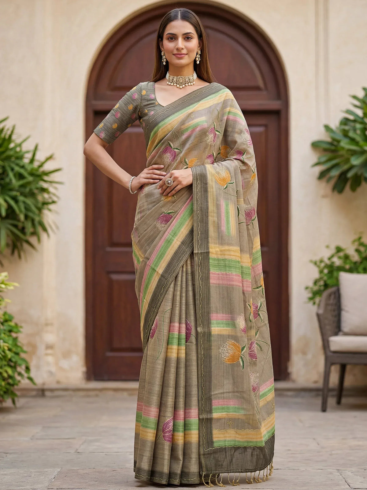 Woman wearing a grey floral print designer saree with colorful stripes and a matching blouse.